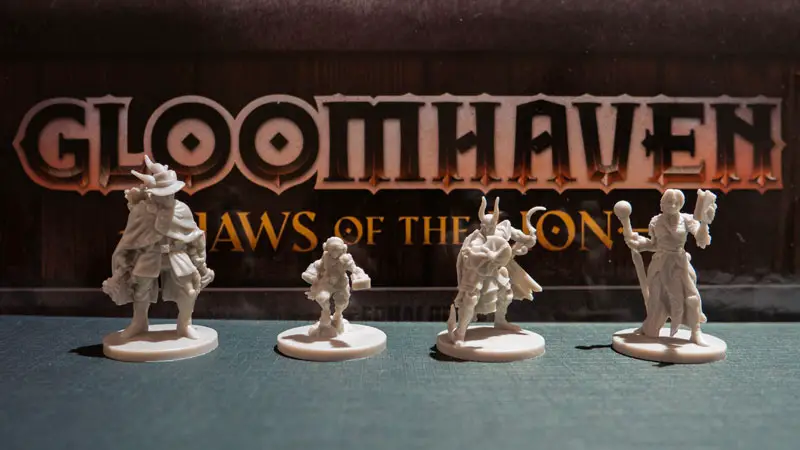 Gloomhaven jaws of the lion miniatures in front of the game box